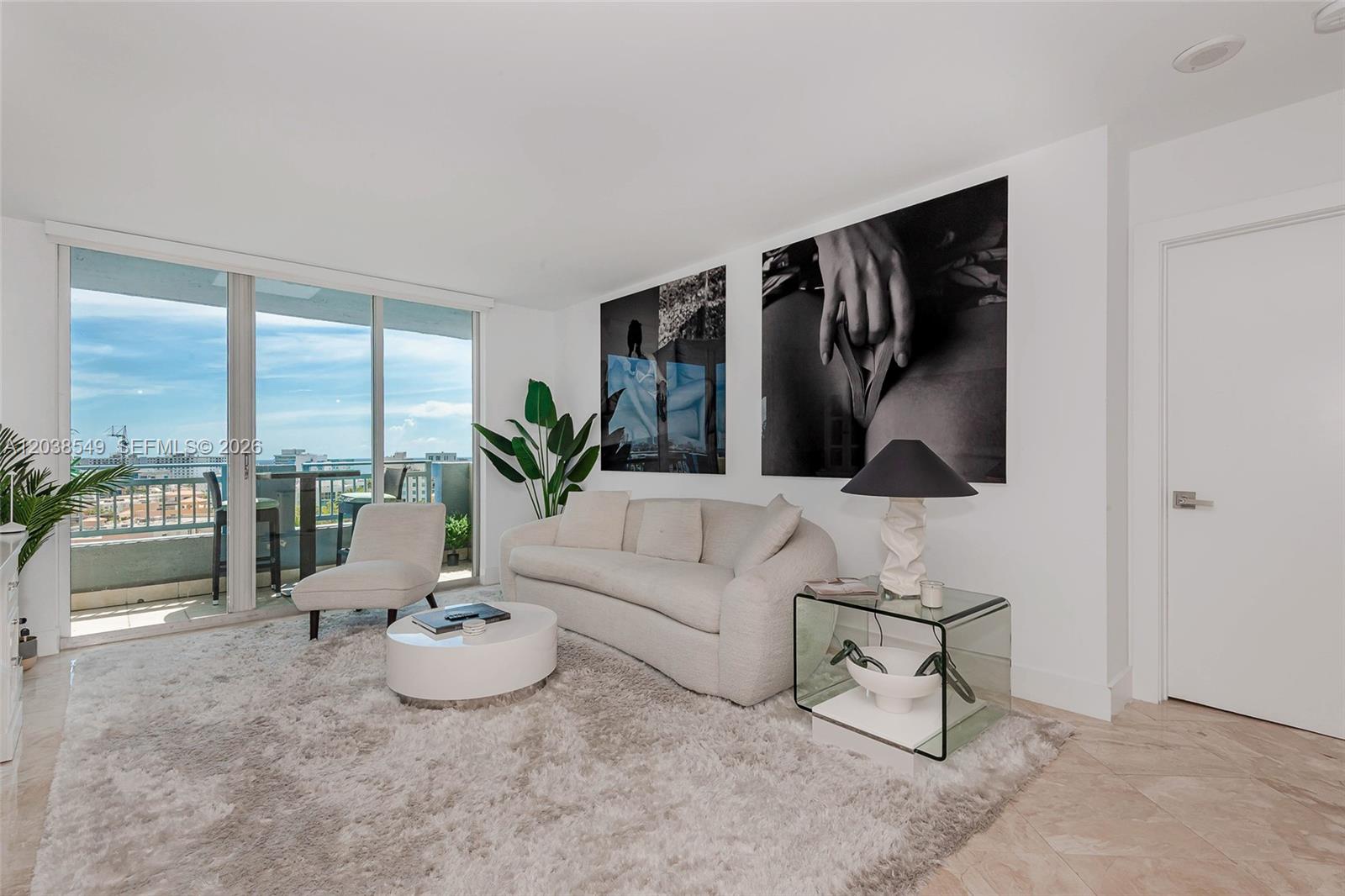 A living room features a white sofa, a glass side table, and large wall art — 90 Alton Rd # 1109, Miami Beach FL 33139, MIAMI BEACH, FL