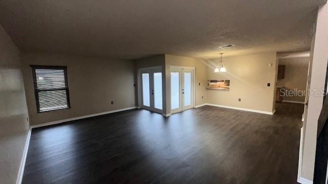 A spacious living room features dark wood-look flooring, a window with blinds, and French doors — 507 HUNTER CIRCLE, KISSIMMEE, FL