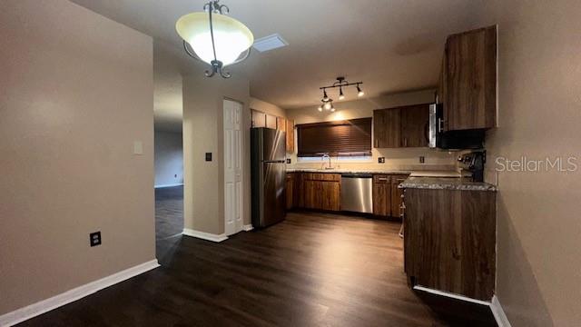 A kitchen with wood cabinets, stainless steel appliances, and dark wood-look flooring — 507 HUNTER CIRCLE, KISSIMMEE, FL