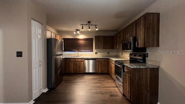 A kitchen featuring wood-grain cabinets, stainless steel appliances, and dark laminate flooring — 507 HUNTER CIRCLE, KISSIMMEE, FL