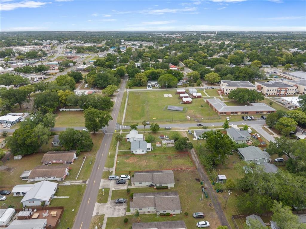An aerial view shows a residential neighborhood with houses, streets, and a large open field — 5540 8TH STREET, ZEPHYRHILLS, FL