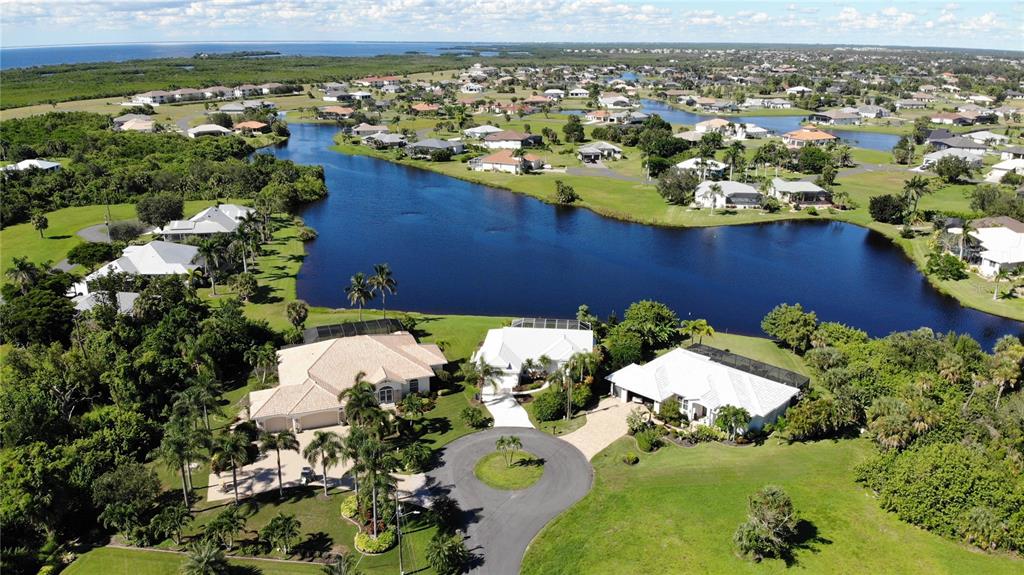 An aerial view shows two large houses with white roofs situated along a lake — 17504 CUILLAGAN COURT, PUNTA GORDA, FL