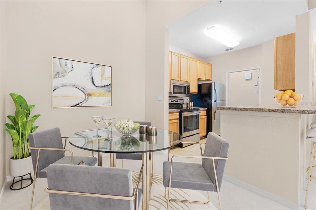 A dining area with a glass table and gray chairs sits adjacent to a kitchen — 10211 COURTNEY PALMS UNIT 303, TAMPA, FL