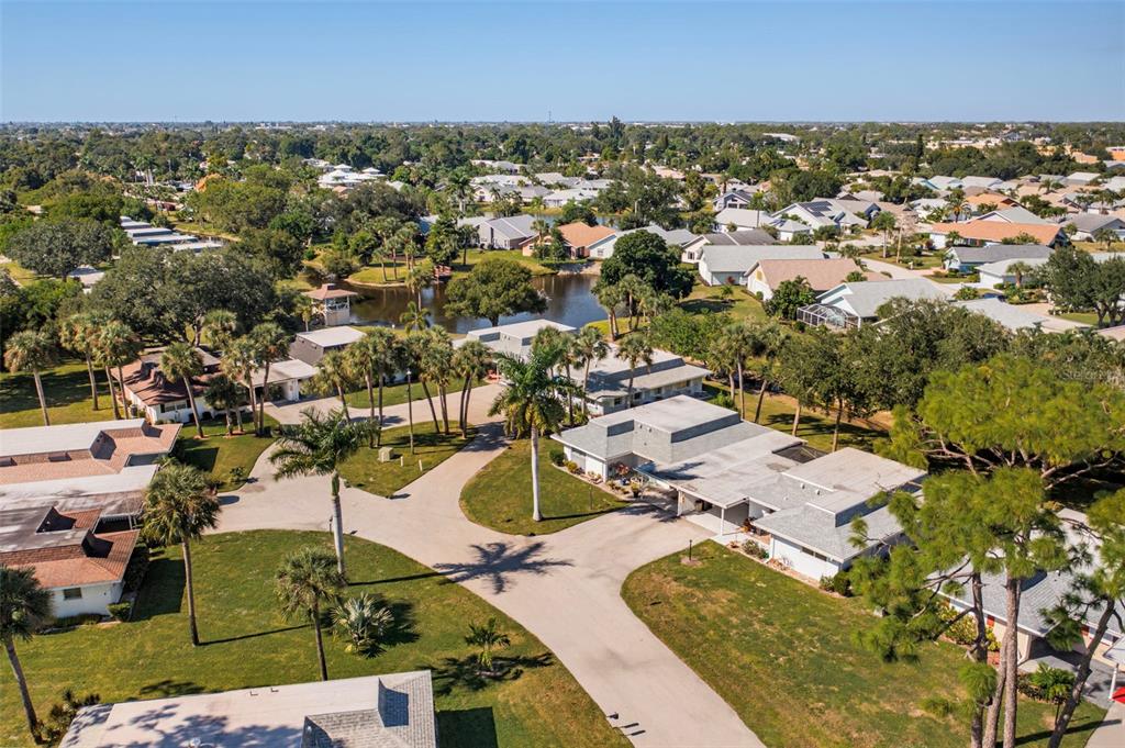 An aerial view shows a residential neighborhood with single-story homes, palm trees, and a pond — 536 PANGOLA DRIVE, NORTH FORT MYERS, FL