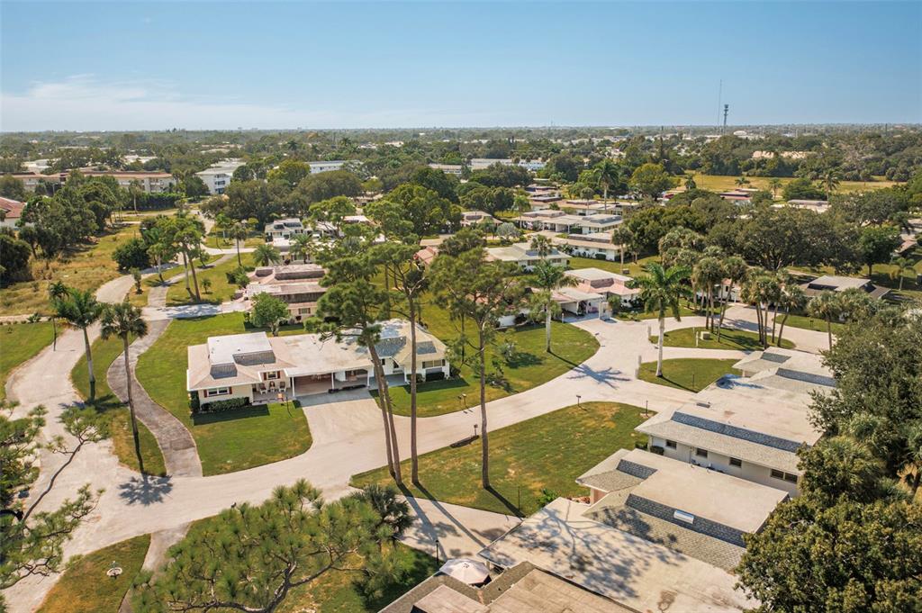 An aerial view shows several single-story homes with flat roofs surrounded by trees and lawns — 536 PANGOLA DRIVE, NORTH FORT MYERS, FL