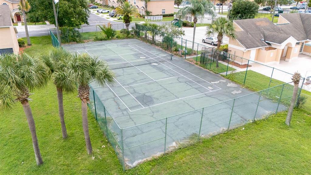 An aerial view of a fenced-in tennis court surrounded by grass and palm trees — 649 CAPTIVA CIRCLE, KISSIMMEE, FL