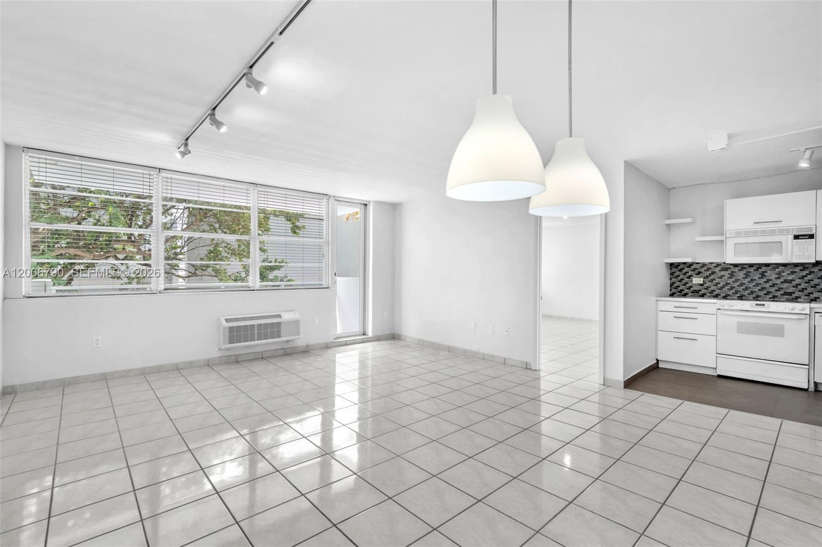 A bright, open-plan living area features white tile flooring, pendant lighting, and an adjacent kitchen — 5313 Collins Ave # 204, Miami Beach FL 33140, MIAMI BEACH, FL