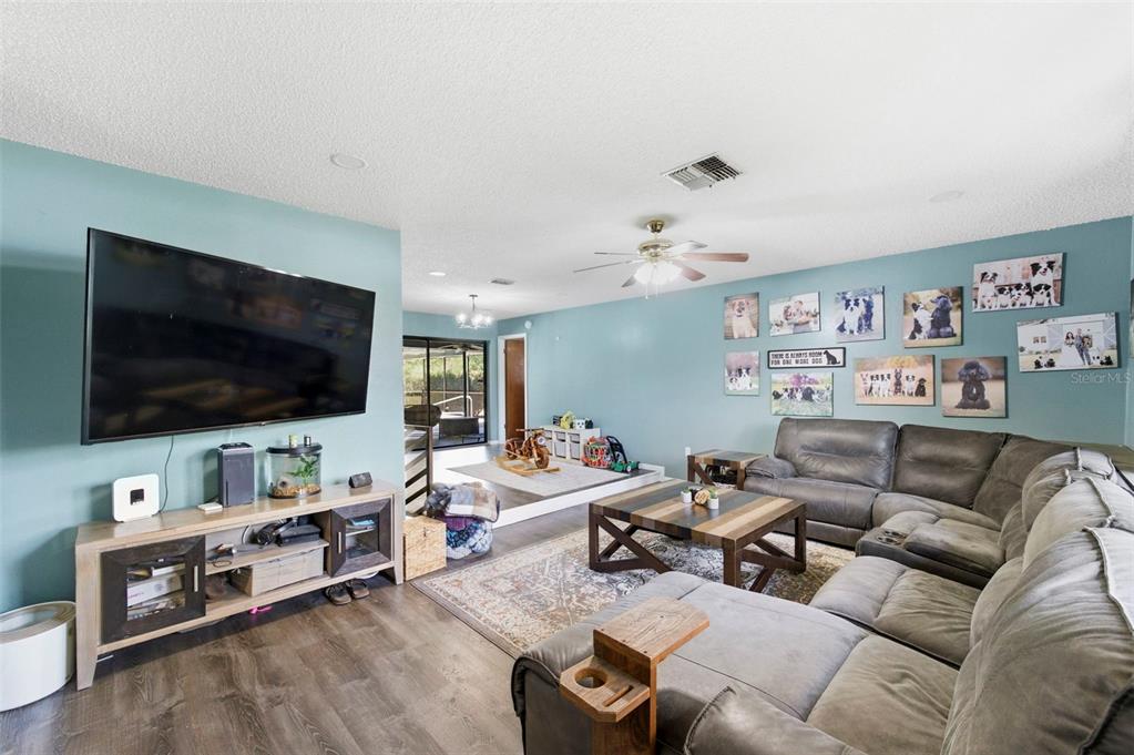 A living room features a grey sectional sofa, wood coffee table, and blue walls — 7377 SKYLARK DRIVE, SPRING HILL, FL