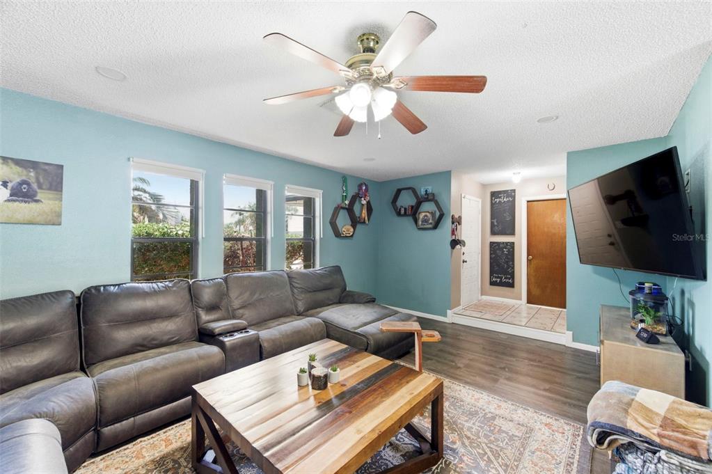 A living room features a grey sectional sofa, a wooden coffee table, and blue walls — 7377 SKYLARK DRIVE, SPRING HILL, FL