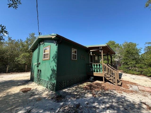 A green mobile home with a wooden porch sits on a sandy lot — 15920 NE 236TH LANE, FORT MC COY, FL
