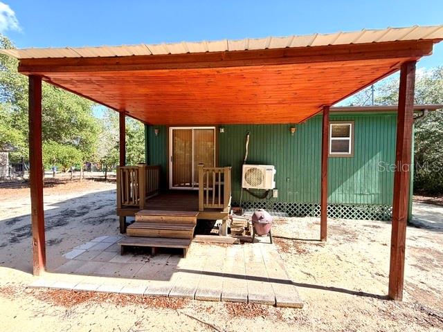 A wooden patio cover extends over a small deck and stairs attached to a green house — 15920 NE 236TH LANE, FORT MC COY, FL