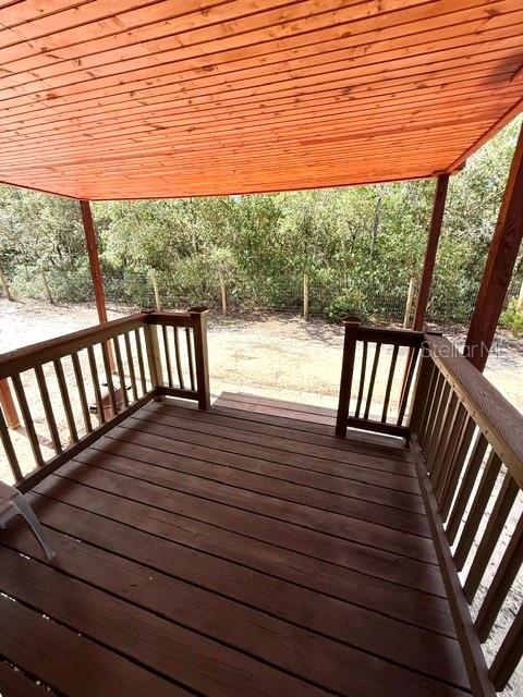 A wooden deck with railings overlooks a wooded area under a covered roof — 15920 NE 236TH LANE, FORT MC COY, FL