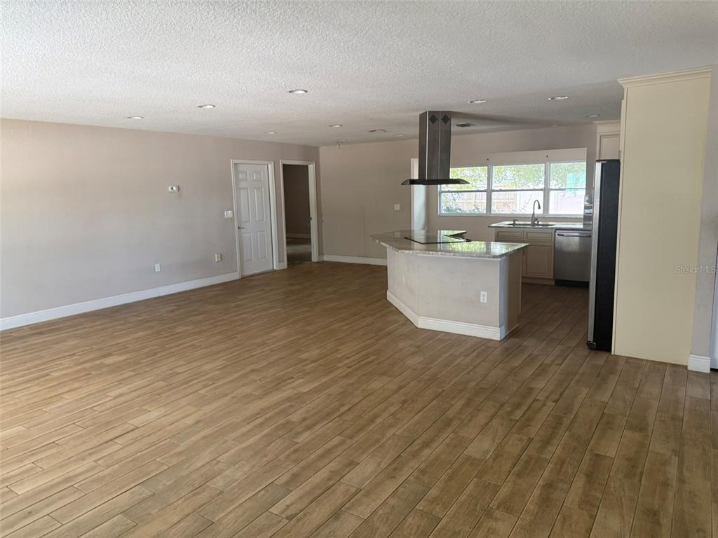 An open-concept kitchen and living area featuring light wood-look flooring and a central island — 4207 21 ST AVENUE W, BRADENTON, FL