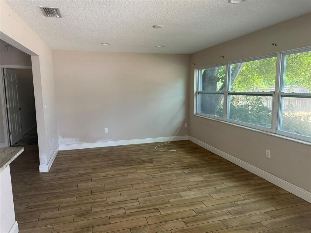 An empty room with wood-look tile flooring, light-colored walls, and large windows — 4207 21 ST AVENUE W, BRADENTON, FL