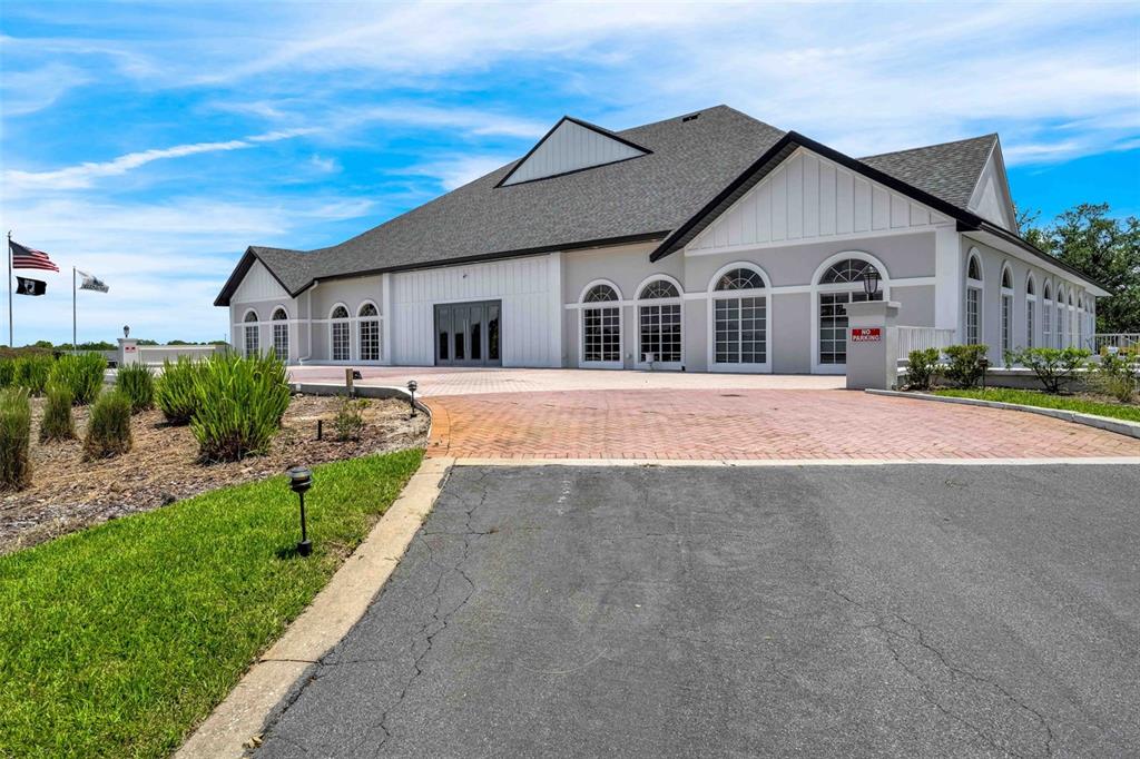 A large, modern building with a brick driveway and arched windows under a blue sky — 9322 SEVE COURT, WEEKI WACHEE, FL