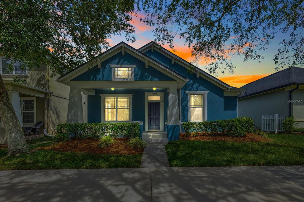 A blue single-story house with a front porch and a walkway at sunset — 14643 TANJA KING BOULEVARD, ORLANDO, FL