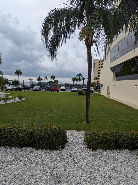 A grassy lawn sits between a building and a parking lot with palm trees — 5915 SEA RANCH DRIVE UNIT 404, HUDSON, FL