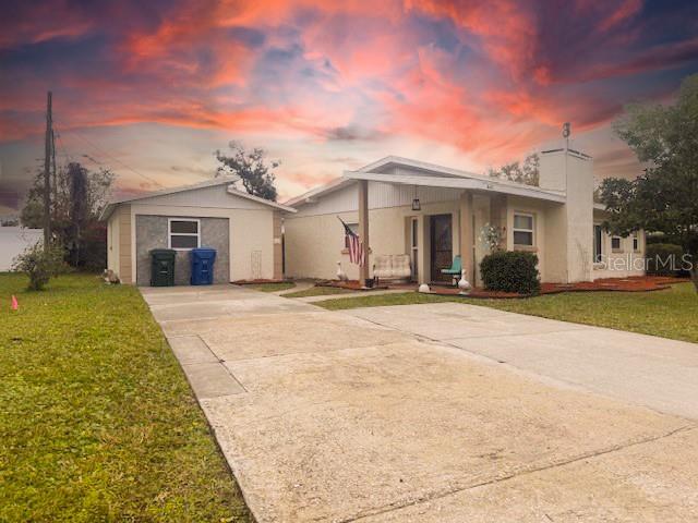 A single-story house with a detached garage and a concrete driveway under a sunset sky — 14472 VALENTINE DRIVE, LARGO, FL