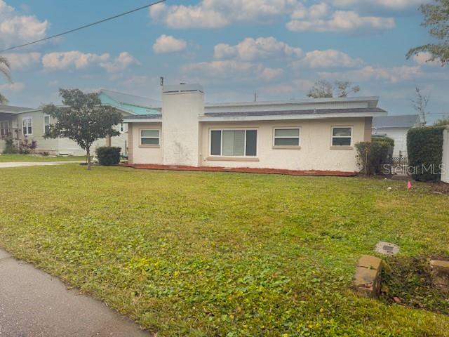 A single-story house with a white stucco exterior and a prominent central chimney — 14472 VALENTINE DRIVE, LARGO, FL