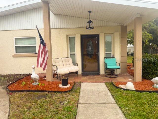 The exterior of a house features a covered porch, a front door, and a small yard — 14472 VALENTINE DRIVE, LARGO, FL