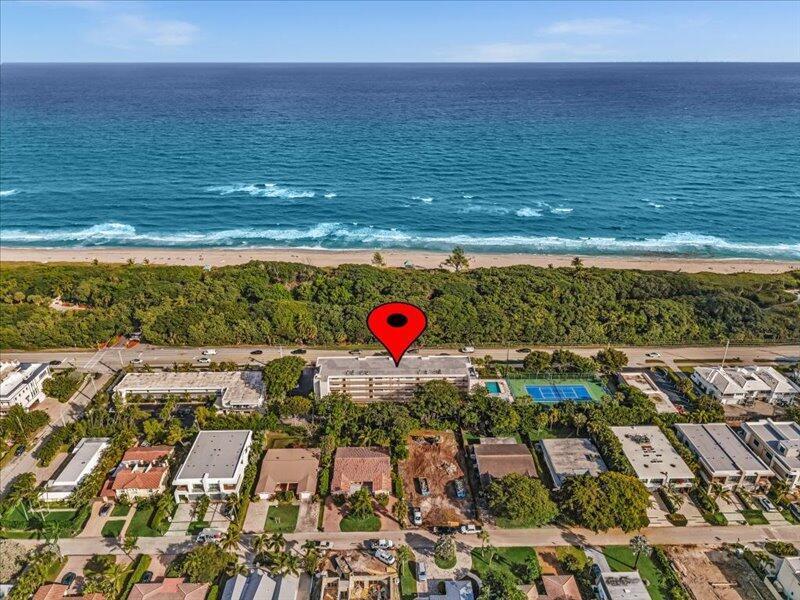 An aerial view shows a beachfront apartment building with a tennis court and surrounding homes — 277 N Ocean Boulevard # 304, Boca Raton FL 33432, BOCA RATON, FL
