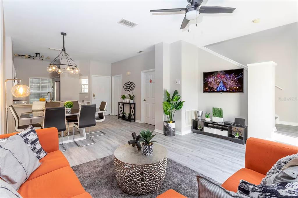 A living room and dining area feature orange sofas, gray flooring, and a ceiling fan — 4505 ALBERTO CIRCLE, KISSIMMEE, FL