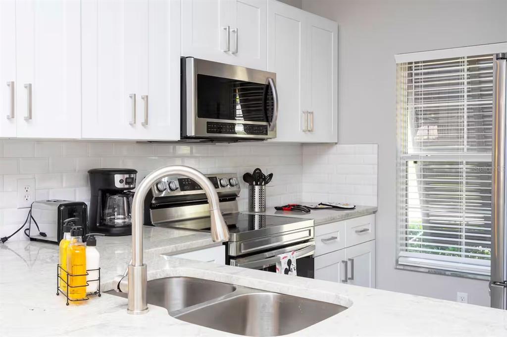 A kitchen features white cabinets, stainless steel appliances, a double sink, and white countertops — 4505 ALBERTO CIRCLE, KISSIMMEE, FL