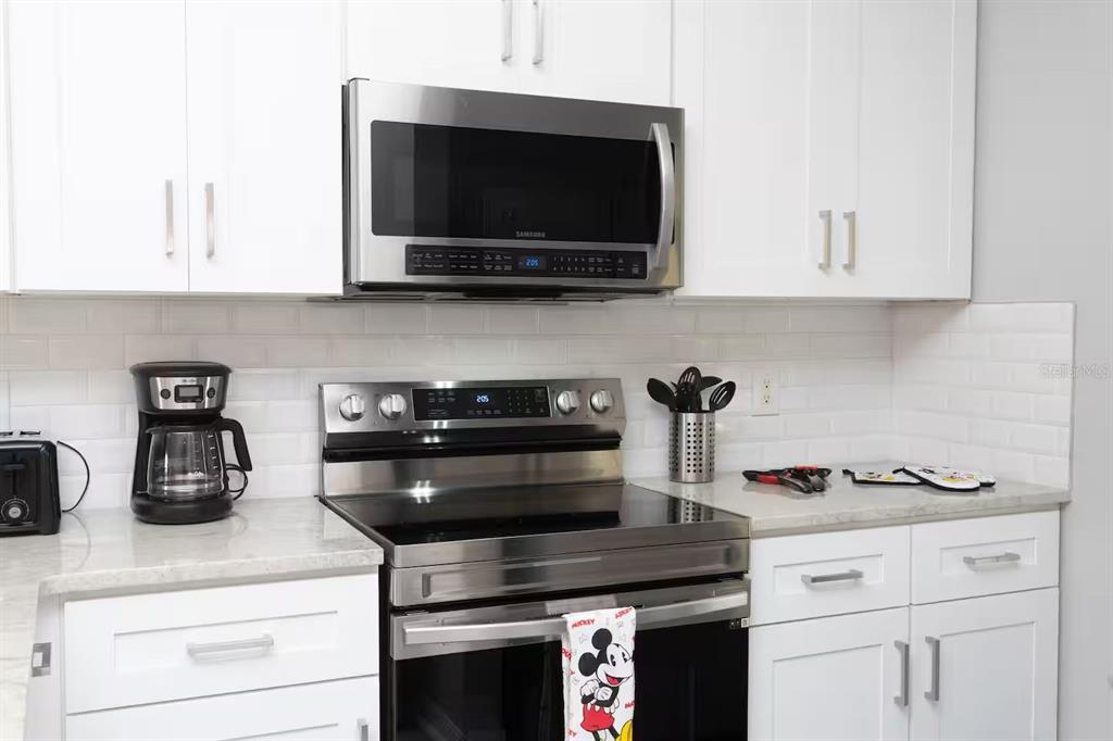 A kitchen features white cabinets, stainless steel appliances, and a white subway tile backsplash — 4505 ALBERTO CIRCLE, KISSIMMEE, FL