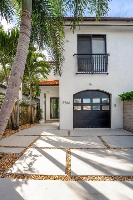 A white two-story house features a black garage door, a balcony, and a concrete paver driveway — 2766 SW 33rd Ave # 2766, Miami FL 33133, MIAMI, FL
