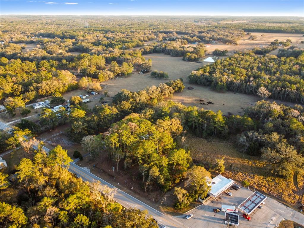 An aerial view shows a gas station adjacent to a wooded lot and rural fields — POWELL ROAD, BROOKSVILLE, FL