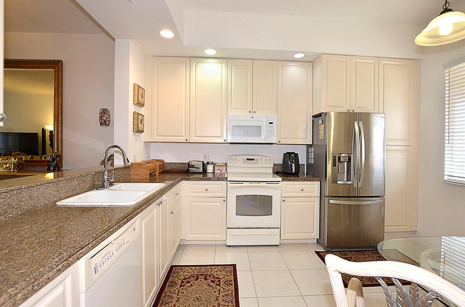 A kitchen with white cabinets, granite countertops, stainless steel appliances, and tile flooring — FORT PIERCE, FL