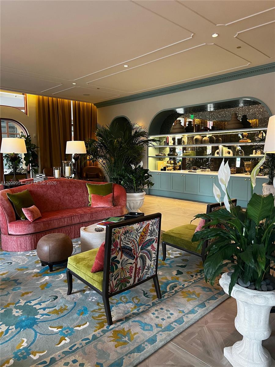 A living room features a red velvet sofa, patterned chairs, and built-in shelving with decor — 2700 NW 2nd Ave # 544, Miami FL 33127, MIAMI, FL