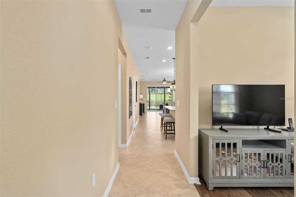 A hallway with tile flooring leads toward an open kitchen and a glass sliding door — 2759 PURPLE MEADOW COURT, MINNEOLA, FL