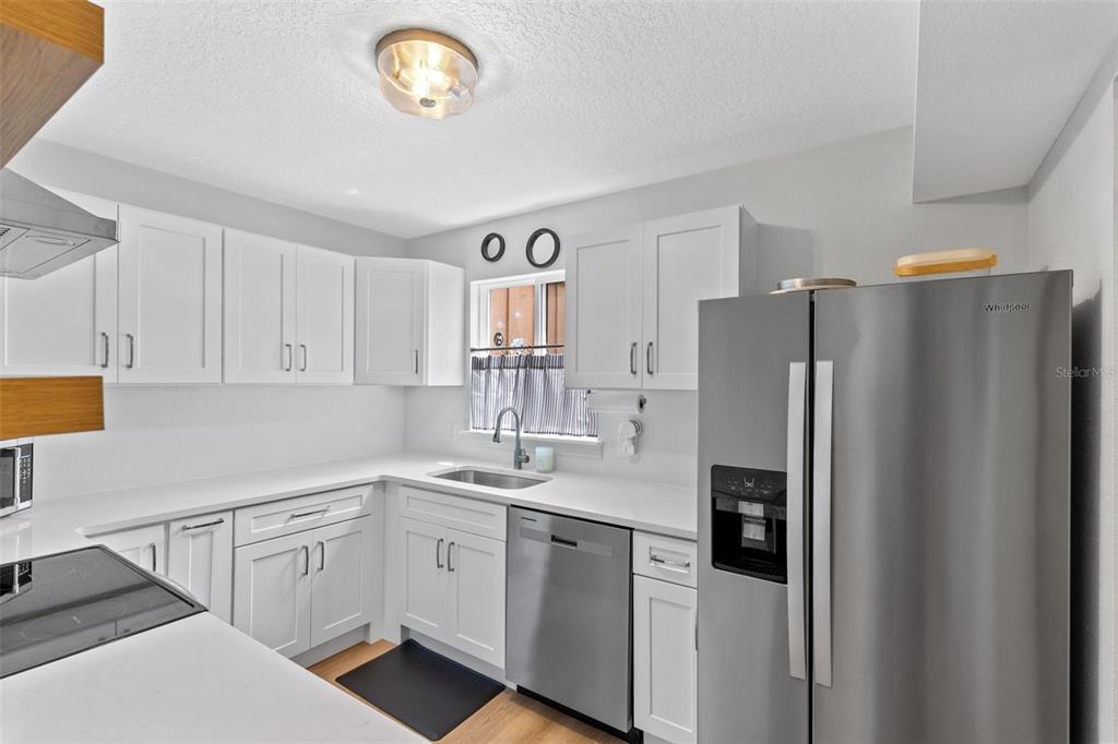 A kitchen features white cabinets, stainless steel appliances, and light-colored countertops — 267 CROWN OAKS WAY UNIT 267, LONGWOOD, FL