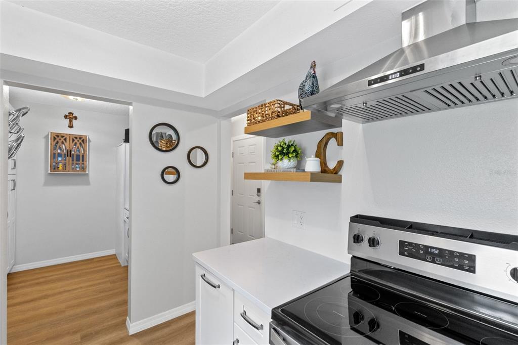 A kitchen features white countertops, open wooden shelving, and a stainless steel range hood — 267 CROWN OAKS WAY UNIT 267, LONGWOOD, FL