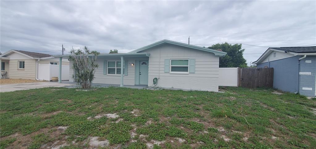 A single-story house with light-colored siding, a covered front porch, and a grassy front yard — 3611 SHERYL HILL DRIVE, HOLIDAY, FL