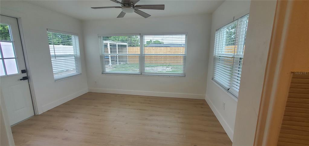 A sunroom with light wood-look flooring, white walls, a ceiling fan, and multiple windows — 3611 SHERYL HILL DRIVE, HOLIDAY, FL