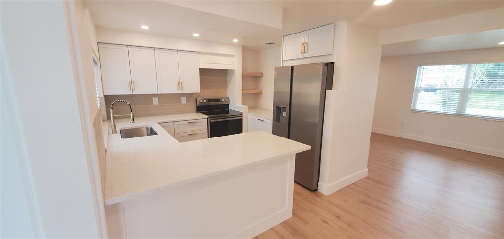 A kitchen features white cabinetry, stainless steel appliances, and a peninsula with quartz countertops — 3611 SHERYL HILL DRIVE, HOLIDAY, FL