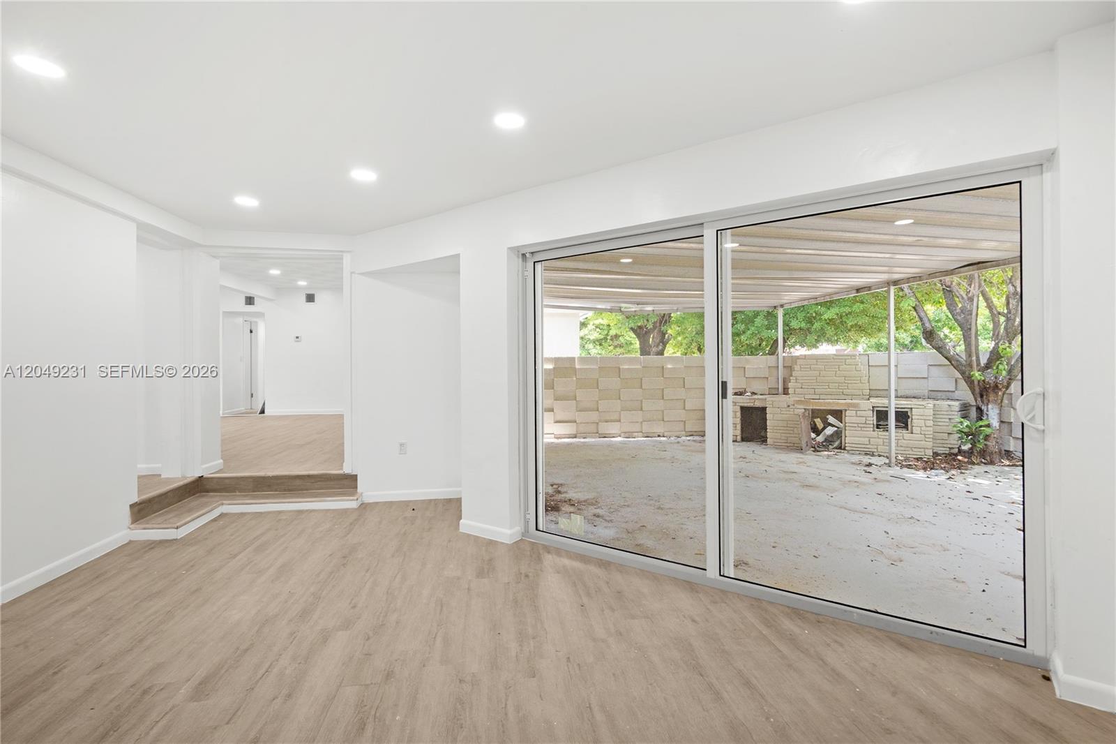 A living room with light wood flooring features a sliding glass door leading to a patio — 1701 NW 19th Ave # 1701, Miami FL 33125, MIAMI, FL
