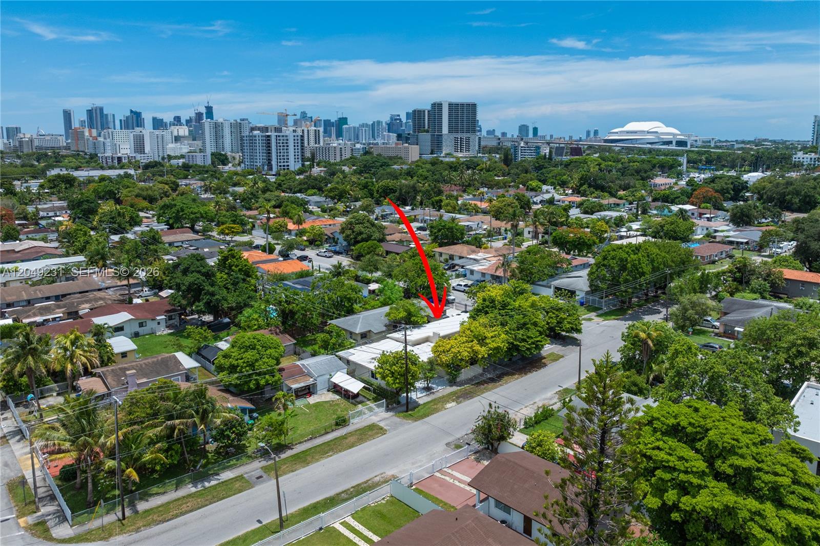 An aerial view shows a single-story house with a white roof surrounded by lush trees — 1701 NW 19th Ave # 1701, Miami FL 33125, MIAMI, FL