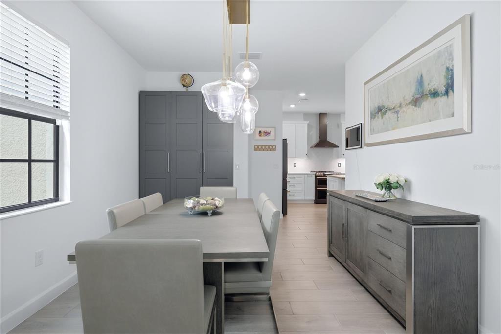 A dining room with a gray table, matching chairs, a sideboard, and a modern light fixture — 11035 HANGING VINE DRIVE, FORT MYERS, FL