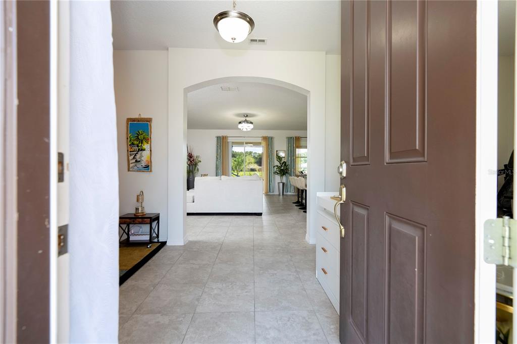 A view from an open front door into a tiled entryway leading to a living area — 603 BRITTLE FERN AVENUE, DELAND, FL