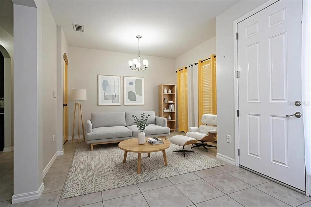 A living room features a gray sofa, a round wooden coffee table, and yellow curtains — 603 BRITTLE FERN AVENUE, DELAND, FL