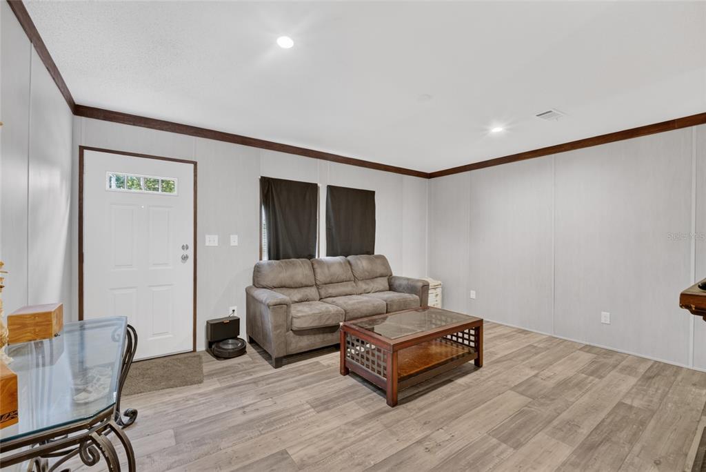 A living room features light-colored wood-look flooring, gray walls, a brown sofa, and a coffee table — 259 OAK STREET, HAWTHORNE, FL