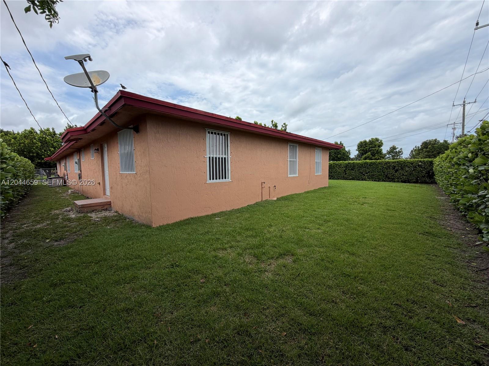 The exterior of a peach-colored house features a satellite dish and security bars on windows — 10530 SW 183rd St # 2, Miami FL 33157, MIAMI, FL