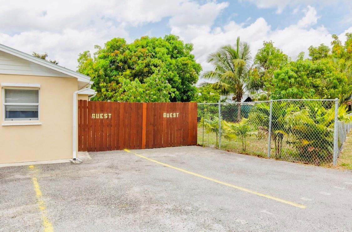 A paved parking area sits beside a building with a wooden fence marked for guest parking — 279 Hach Lane, West Palm Beach FL 33415, WEST PALM BEACH, FL
