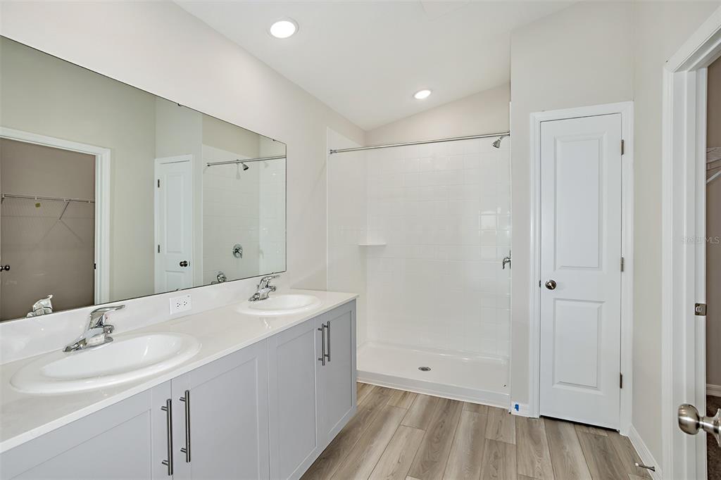 A bathroom features a double vanity with gray cabinets, a white countertop, and a walk-in shower — 15204 MAUDE LANDING LOOP, WIMAUMA, FL