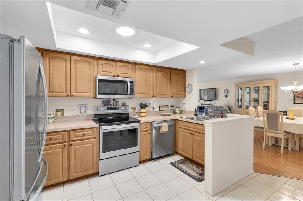 A kitchen with light wood cabinets, stainless steel appliances, and a tile floor — 11436 VERSAILLES LANE, PORT RICHEY, FL