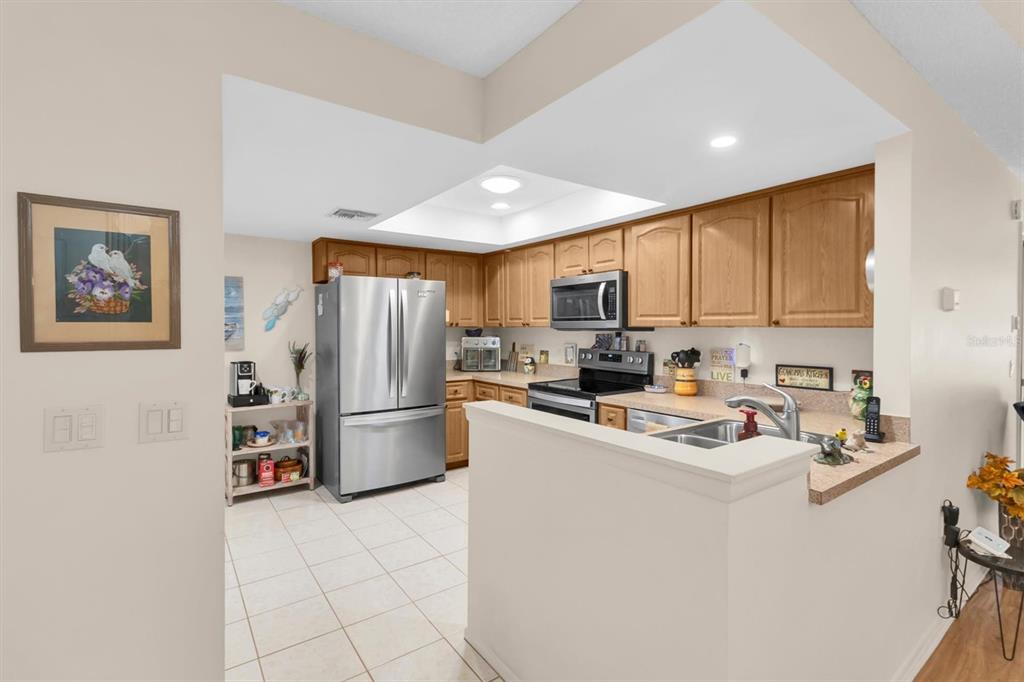 A kitchen with light wood cabinets, stainless steel appliances, and a tiled floor — 11436 VERSAILLES LANE, PORT RICHEY, FL