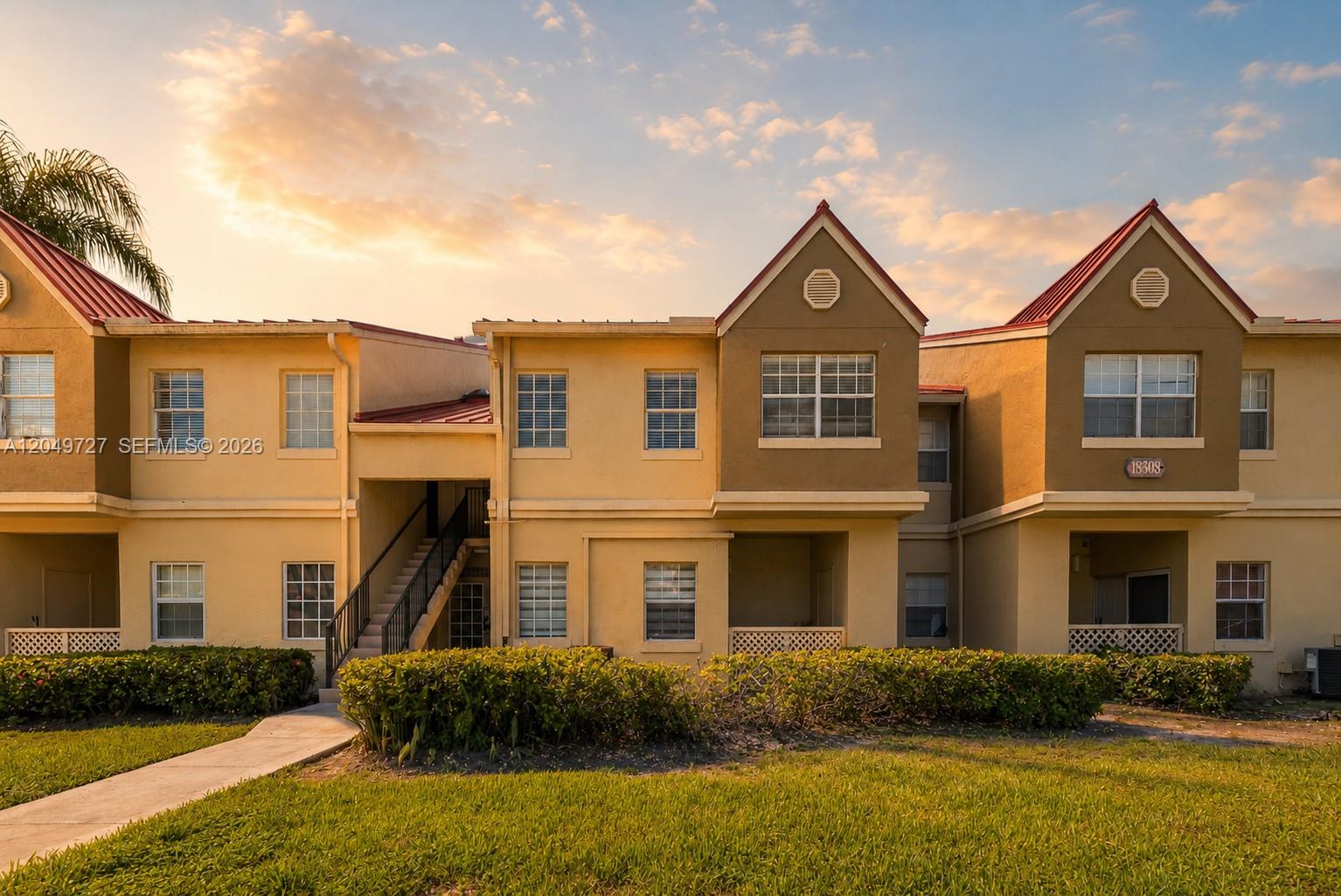 A two-story apartment building with tan stucco walls, red metal roofs, and exterior staircases — 18308 NW 68th Ave # B, Hialeah FL 33015, HIALEAH, FL
